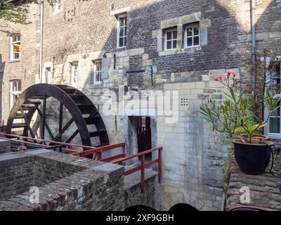 Moulin à eau avec roue de moulin et balustrades rouges devant un vieux bâtiment en briques avec plante en pot, maastricht, pays-bas Banque D'Images