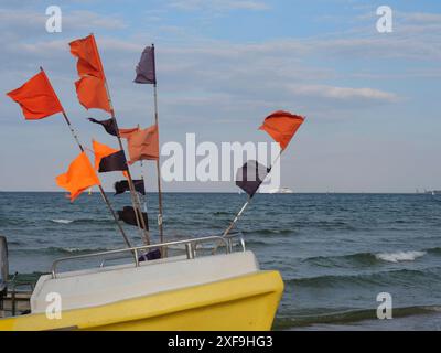 Bateau de pêche avec drapeaux colorés sur le rivage, mer calme et ciel dégagé, sopot, mer baltique, pologne Banque D'Images