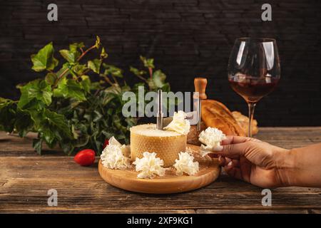 Femme tranchant le délicieux fromage tete de moine d'une girolle traditionnelle sur une table en bois rustique Banque D'Images