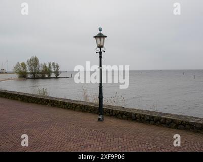 Un lampadaire solitaire sur une route en bord de mer sous un ciel nuageux, urk, pays-bas Banque D'Images