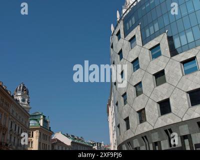 Façade en verre moderne avec structure hexagonale à côté de bâtiments historiques sous un ciel bleu, Vienne, Autriche Banque D'Images