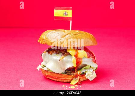 Hamburger au bœuf asturien. Burger brioche pain, oignon, fromage Becom, moutarde, ketchup, sur fond rouge. Espagne Banque D'Images