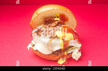 Hamburger au bœuf asturien. Burger brioche pain, oignon, fromage Becom, moutarde, ketchup, sur fond rouge. Espagne Banque D'Images