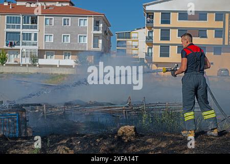 Feu dans le champ près de la ville. Pompier éteint un incendie. Banque D'Images