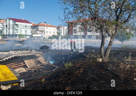 Feu dans le champ près de la ville. Pompier éteint un incendie. Banque D'Images