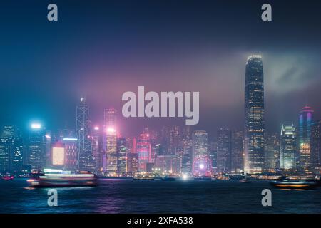 Magnifique paysage urbain nocturne de gratte-ciel d'affaires illuminé coloré avec spectacle d'éclairage laser sur le port Victoria en journée brumeuse à Hong Banque D'Images