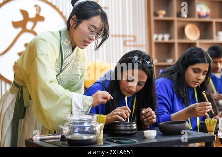 (240702) -- PÉKIN, 2 juillet 2024 (Xinhua) -- les étudiants apprennent l'art du thé sous l'instruction d'un étudiant (l) de l'Université normale du Xinjiang pendant le camp de printemps 2024 'Chinese Bridge' pour les étudiants des pays SCO, dans la région autonome ouïgoure du Xinjiang, au nord-ouest de la Chine, 15 avril 2024. (Xinhua/Wang Fei) Banque D'Images