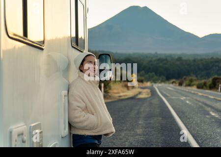 Belle jeune femme asiatique avec bonnet penché sur le camping-car et la montagne du volcan au bord de la route le matin à la Nouvelle-Zélande Banque D'Images