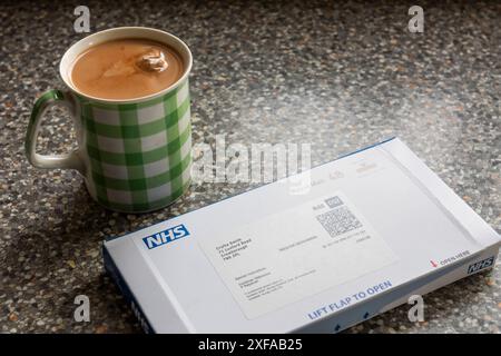 Trop important pour remettre à plus tard ou ignorer, une lettre du NHS pour entreprendre la détection du cancer de l'intestin avec un kit d'échantillonnage de retour à la maison, en pensant à cela avec Cuppa Banque D'Images