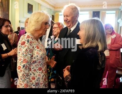 La reine Camilla (à gauche) s'adresse à Lady Elizabeth McCall Smith (à droite) et à son mari Sir Alexander McCall Smith (au centre) lors d'une célébration pour ceux qui font la promotion de l'alphabétisation écossaise au Palace of Holyroodhouse à Édimbourg, y compris les propriétaires de librairies et les auteurs, et des représentants du Festival international du livre d'Édimbourg et du Scottish Book Trust. Date de la photo : mardi 2 juillet 2024. Banque D'Images