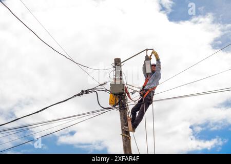 électricien joint les fils du nouvel éclairage led à installer sur le poteau. Banque D'Images