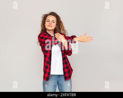 Femme brune portant des vêtements décontractés faisant de l'exercice devant un mur gris clair. Banque D'Images