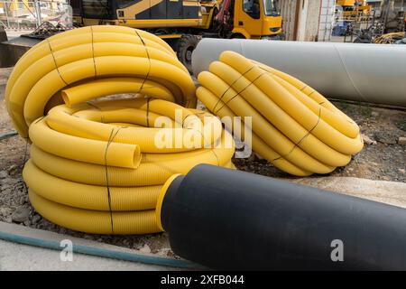 Tuyau ou tuyau nervuré. Rouleau de PVC de tuyau flexible ondulé industriel rouge posé sur le sol. Isolation rouge pour chantier de construction de câbles Banque D'Images