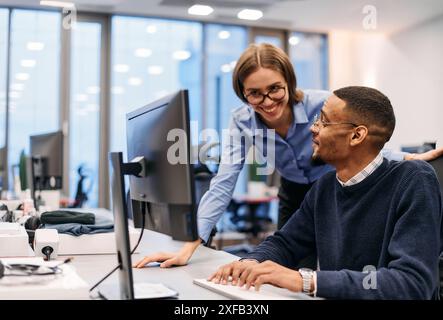 Collaboration numérique : femme d'affaires blonde et partenaire afro-américain examinant des documents en ligne Banque D'Images