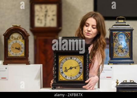 Londres, Royaume-Uni. 2 juillet 2024. Un membre du personnel avec « une intéressante horloge de table en ébène quart de train jumelé à la fin du XVIIe siècle, et plus tard », (est. £15 000 - £25,000), dans le cadre de la vente Fine Clocks, lors d'un aperçu des Bonhams Summer Classics Sales. Les œuvres seront mises en vente dans les galeries Bonhams New Bond Street et Knightsbridge. 3, 4 et 5 juillet. Credit : Stephen Chung / Alamy Live News Banque D'Images