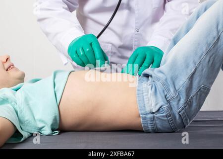 Un médecin en gants médicaux verts écoute les bronches avec un stéthoscope d'une petite fille de sept ans. Concept de maladie des voies respiratoires, bron Banque D'Images