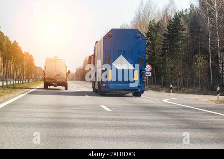 Un camion avec une semi-remorque pour le transport de verre transporte des marchandises le long de la route au printemps contre le soleil en toile de fond. Cargaison fragile, copie Banque D'Images