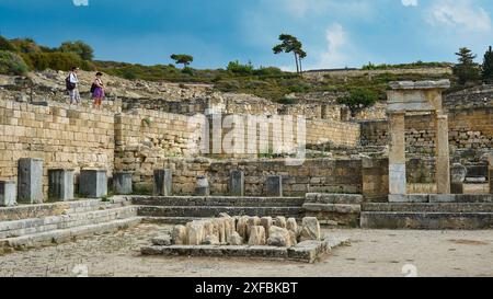 Ruines historiques avec plusieurs structures en pierre et peu de visiteurs sous le ciel bleu, ancienne maison de puits, Kamiros, site archéologique, ancienne ville Banque D'Images