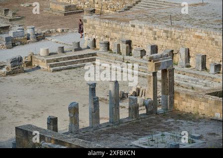 Ruines d'un ancien temple avec des colonnes de pierre et un visiteur près de murs de pierre, Kamiros, site archéologique, ville antique, Fondation des Grecs doriques Banque D'Images