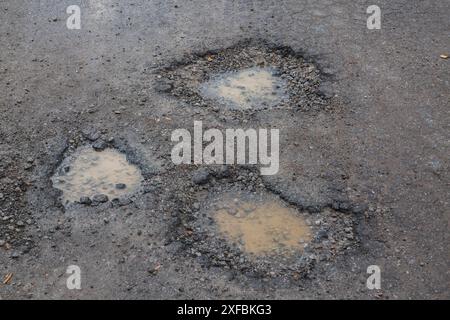 Nids de poule avec de l'eau de pluie sur la surface de route asphaltée noire humide au printemps, Montréal, Québec, Canada Banque D'Images