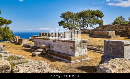 Anciens murs et ruines dans le paysage ensoleillé avec vue sur la mer et les arbres, ciel bleu au-dessus, Kamiros, site archéologique, ancienne ville, Fondation de Doric Banque D'Images