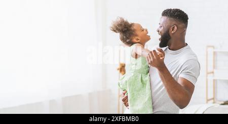 Heureux père et fille dansant dans un salon lumineux Banque D'Images