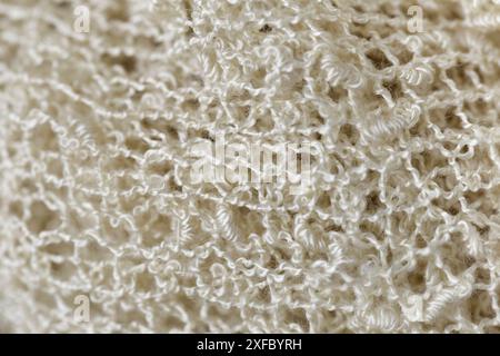 Un gros plan d'un tricot blanc avec beaucoup de texture. Concept de chaleur et de confort, car le tissu est doux et confortable. Le motif complexe du K. Banque D'Images