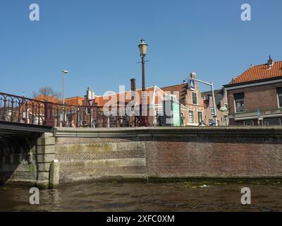 Pont sur un canal avec lampadaire et maisons en briques avec des toits rouges en arrière-plan par une journée ensoleillée, haarlem, pays-Bas Banque D'Images