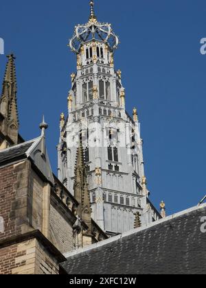 Tour d'église haute, richement décorée avec des accents dorés, contre un ciel bleu et des détails gothiques Banque D'Images