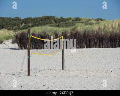 Un filet de volley-ball se dresse sur la plage de sable, entourée de végétation et de temps ensoleillé, helgoland, mer du Nord, allemagne Banque D'Images