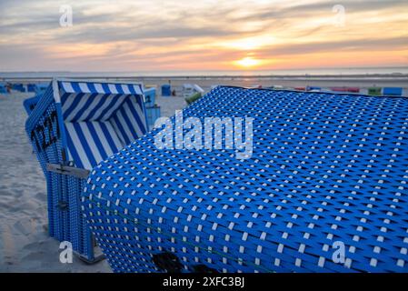 Gros plan d'un panier de plage bleu avec vue sur d'autres paniers et la mer au coucher du soleil, langeoog, frise orientale, allemagne Banque D'Images