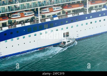 Civitavecchia, Italie- 22 mai 2024 : bateau pilote portuaire à côté du bateau de croisière Marella Voyager subissant les formalités de départ Banque D'Images