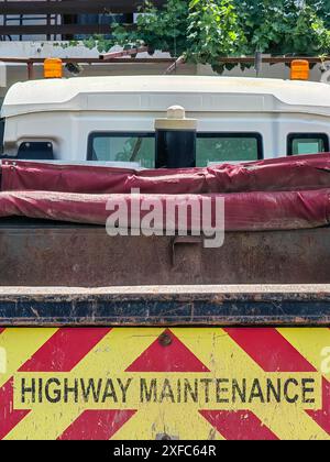 Travail en cours. Entretien routier, lettres noires sur remorque rouge et jaune. Banque D'Images