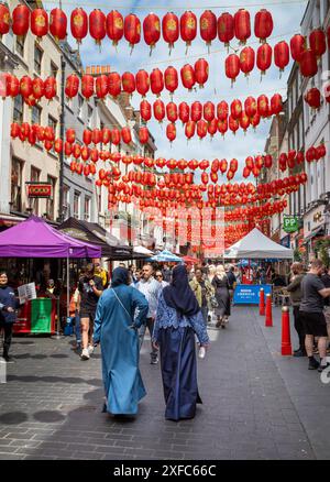 Londres / Royaume-Uni - juin 28 2024 : deux femmes musulmanes portant des hijabs marchent sous des lanternes rouges dans Chinatown à Londres, Royaume-Uni. Banque D'Images