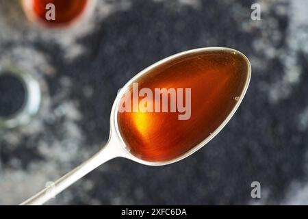 Cumin noir ou huile de graines de Nigella sativa sur une cuillère en métal, vue de dessus. Supplément anti-inflammatoire et antioxydant sain. Banque D'Images