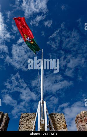 Le drapeau portugais flotte au-dessus des remparts de pierre du Castelo de São Jorge, sur un ciel bleu éclatant Banque D'Images