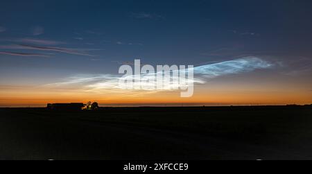 Les nuages noctiluents (NLC) ressortent d'un blanc argenté brillant contre le ciel crépusculaire du soir au-dessus de la campagne néerlandaise Banque D'Images