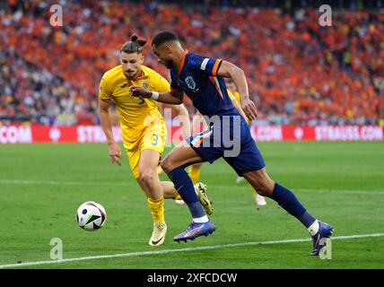 Le roumain Radu Dragusin et le néerlandais Cody Gakpo se battent pour le ballon lors de l'UEFA Euro 2024, 16e manche au Munich Football Arena à Munich, en Allemagne. Date de la photo : mardi 2 juillet 2024. Banque D'Images