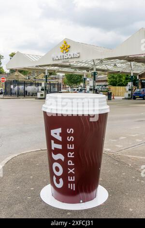 Un grand panneau publicitaire Costa Coffee devant une station-service Morrisons. Banque D'Images