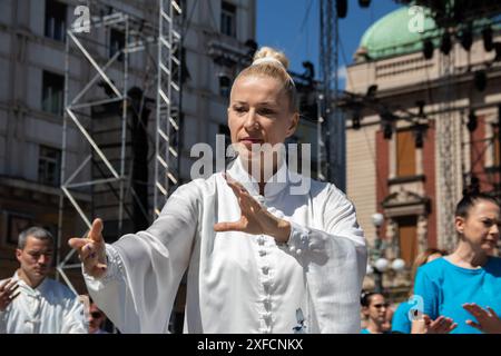 Un maître de Tai Chi serein dans un costume blanc fluide se produit gracieusement dans une rue animée, ses mouvements fluides contrastant avec la toile de fond urbaine vibrante Banque D'Images