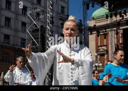 Un maître de Tai Chi serein dans un costume blanc fluide se produit gracieusement dans une rue animée, ses mouvements fluides contrastant avec la toile de fond urbaine vibrante Banque D'Images