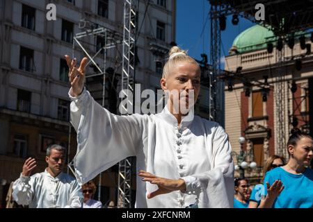 Un maître de Tai Chi serein dans un costume blanc fluide se produit gracieusement dans une rue animée, ses mouvements fluides contrastant avec la toile de fond urbaine vibrante Banque D'Images