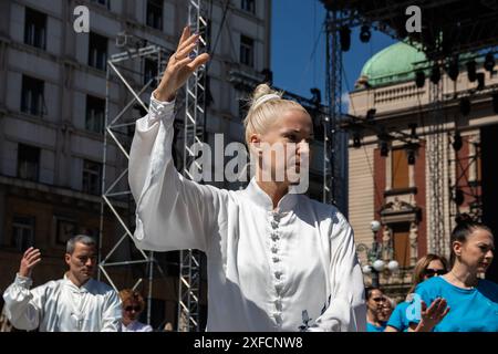 Un maître de Tai Chi serein dans un costume blanc fluide se produit gracieusement dans une rue animée, ses mouvements fluides contrastant avec la toile de fond urbaine vibrante Banque D'Images