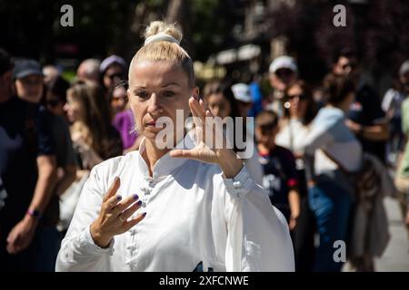 Un maître de Tai Chi serein dans un costume blanc fluide se produit gracieusement dans une rue animée, ses mouvements fluides contrastant avec la toile de fond urbaine vibrante Banque D'Images