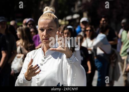 Un maître de Tai Chi serein dans un costume blanc fluide se produit gracieusement dans une rue animée, ses mouvements fluides contrastant avec la toile de fond urbaine vibrante Banque D'Images