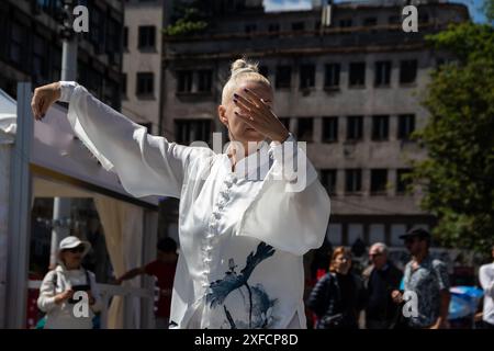 Un maître de Tai Chi serein dans un costume blanc fluide se produit gracieusement dans une rue animée, ses mouvements fluides contrastant avec la toile de fond urbaine vibrante Banque D'Images