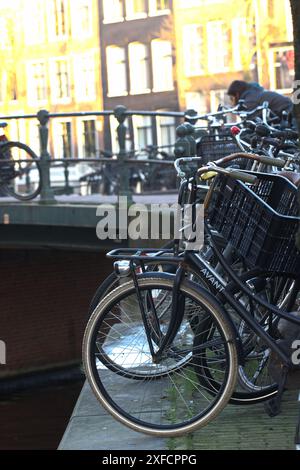 Vélos, vélos et vélos garés sur la route et contre le mur sur le pont sur le canal ensoleillé d'Amstel, Amsterdam ville pays-Bas. Banque D'Images