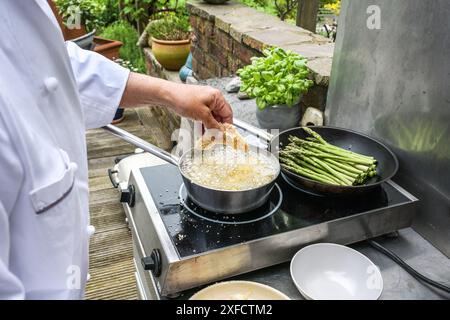 Cuire des morceaux de poulet panko panés à friture dans une casserole d'huile chaude dans une cuisine extérieure rustique, concept de cuisson d'été, foyer sélectionné, profondeur étroite de Banque D'Images