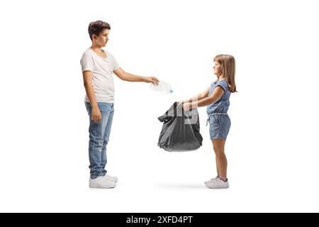 Petite fille tenant un sac à déchets en plastique noir ouvert et adolescent jetant une bouteille isolé sur fond blanc Banque D'Images