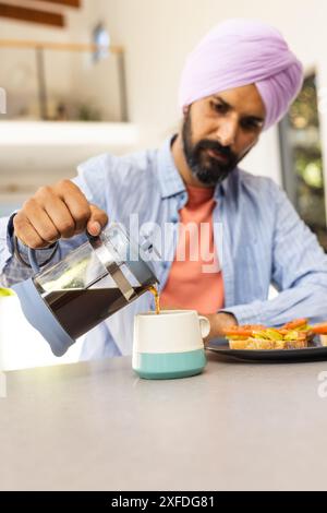 Verser le café de la presse française dans la tasse, homme prenant le petit déjeuner à la maison Banque D'Images